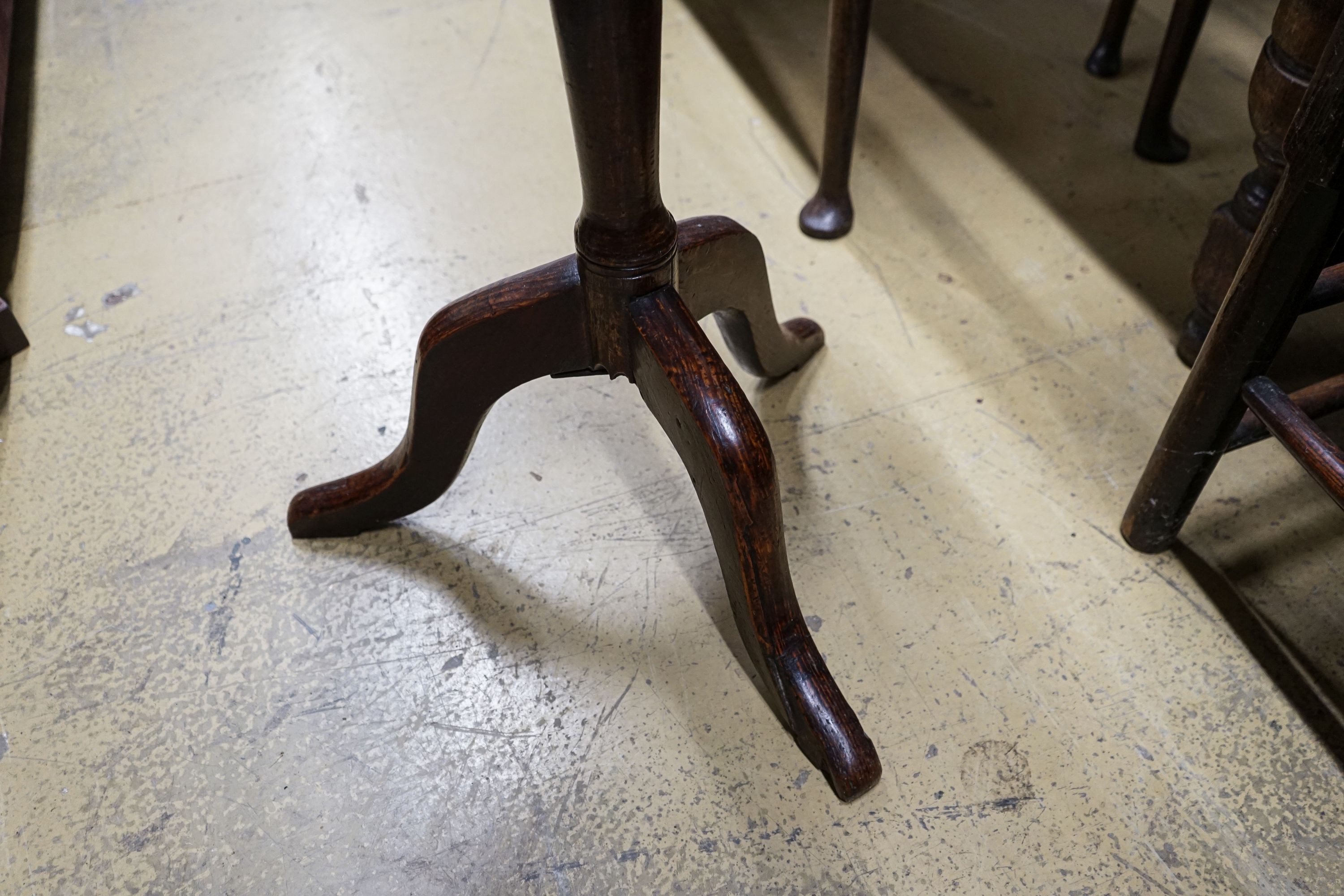 A George III oak tripod table, with circular top and slender baluster stem, diameter 46cm height 72cm